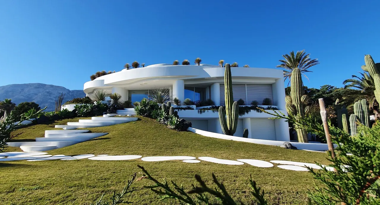 Casa blanca contemporánea con jardín de cactus bajo cielo despejado