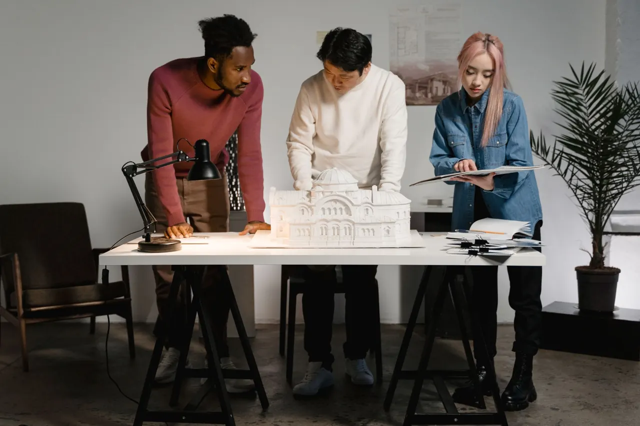 Tres personas del estudio alrededor de una maqueta sobre la mesa